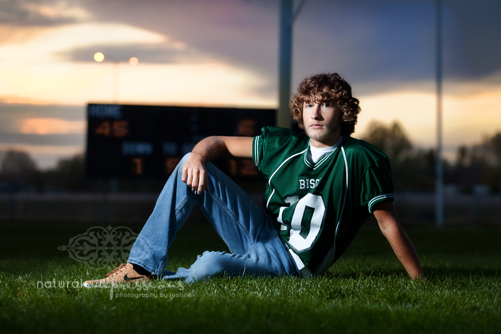 senior boy at night by football scoreboard