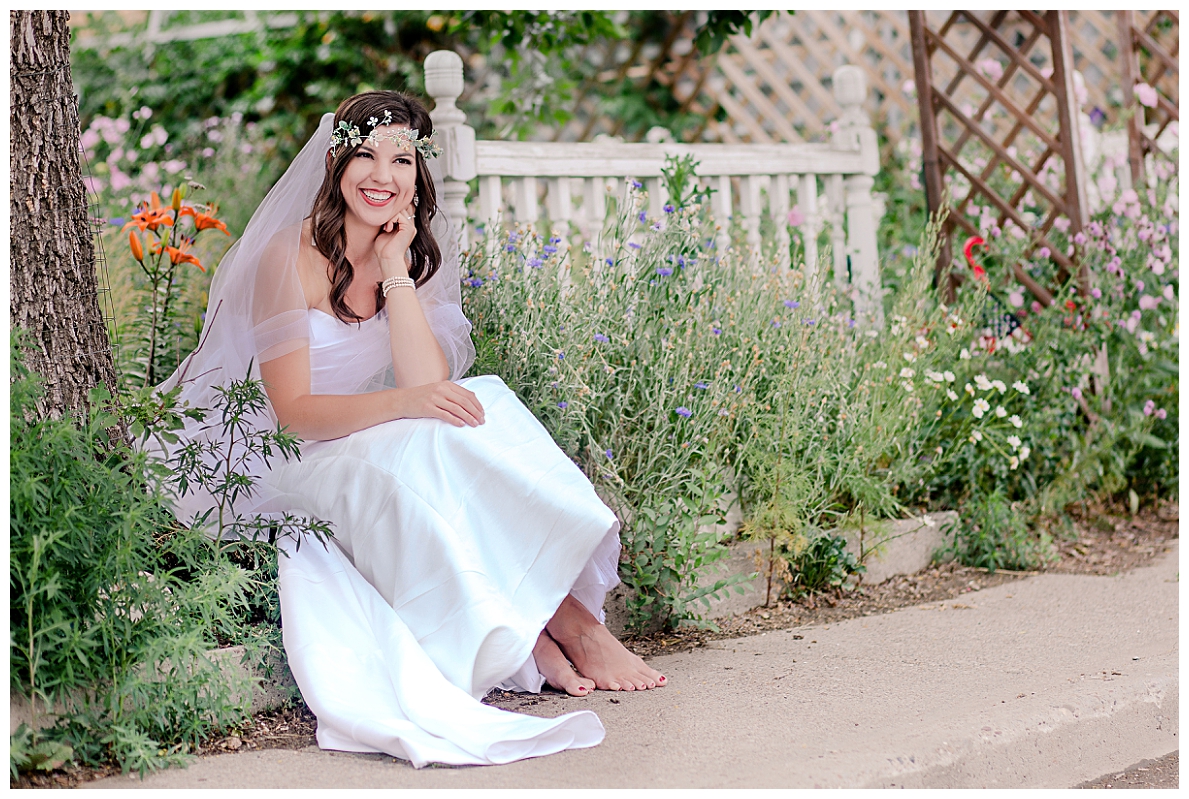 outdoor bride with bare feet sits in English garden  wearing flower headband and veil