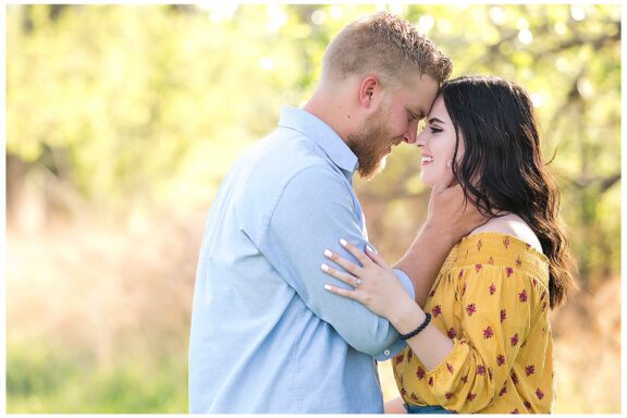 Engaged couple in a field during golden hour evening light