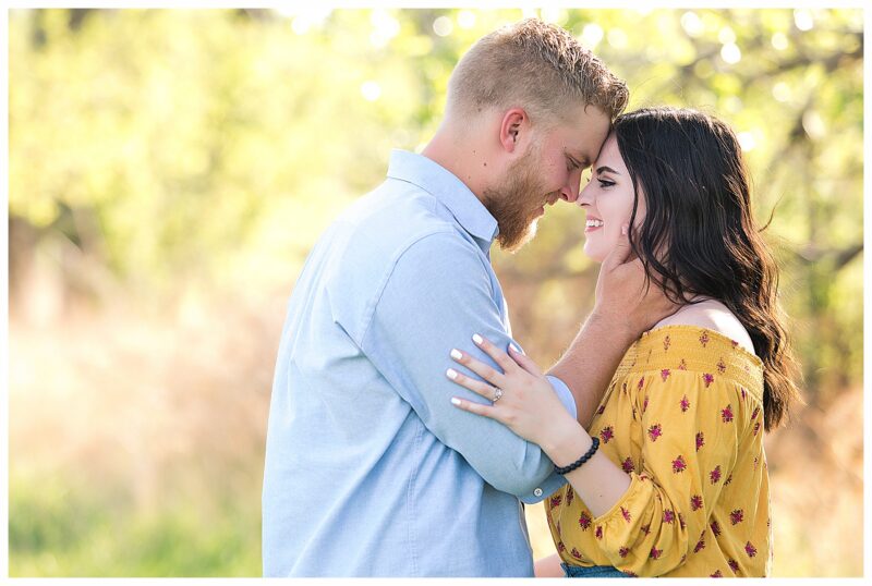 Engaged couple in a field during golden hour evening light