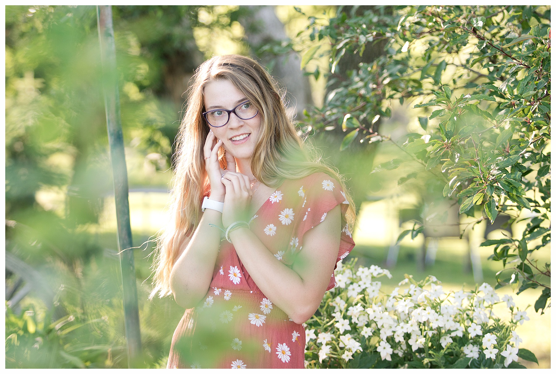 senior girl peeks throough branches