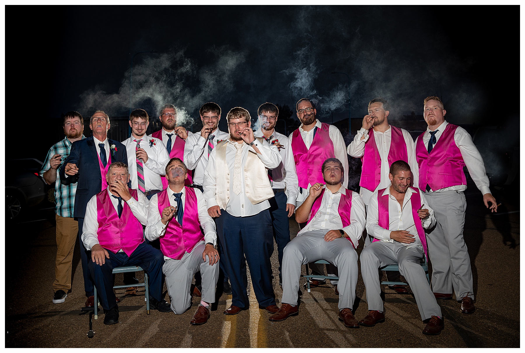 groom in navy and cream and grooms men in grey and pink smoke cigars at night with back light