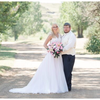 Bride in pink gown and glasses with groom in navy at Lake Tschida