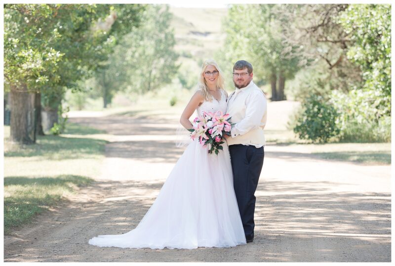 Bride in pink gown and glasses with groom in navy at Lake Tschida