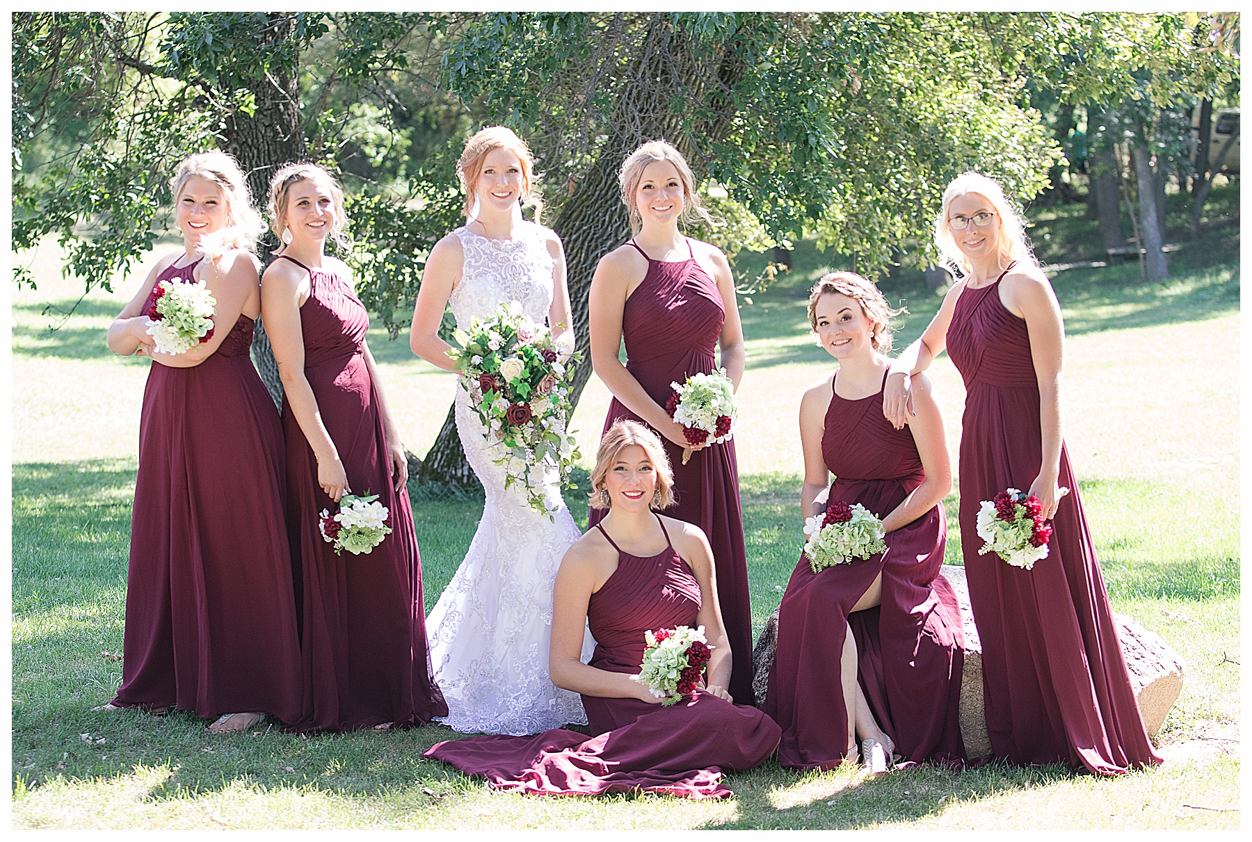 bride and bridesmaids pose around  boulder