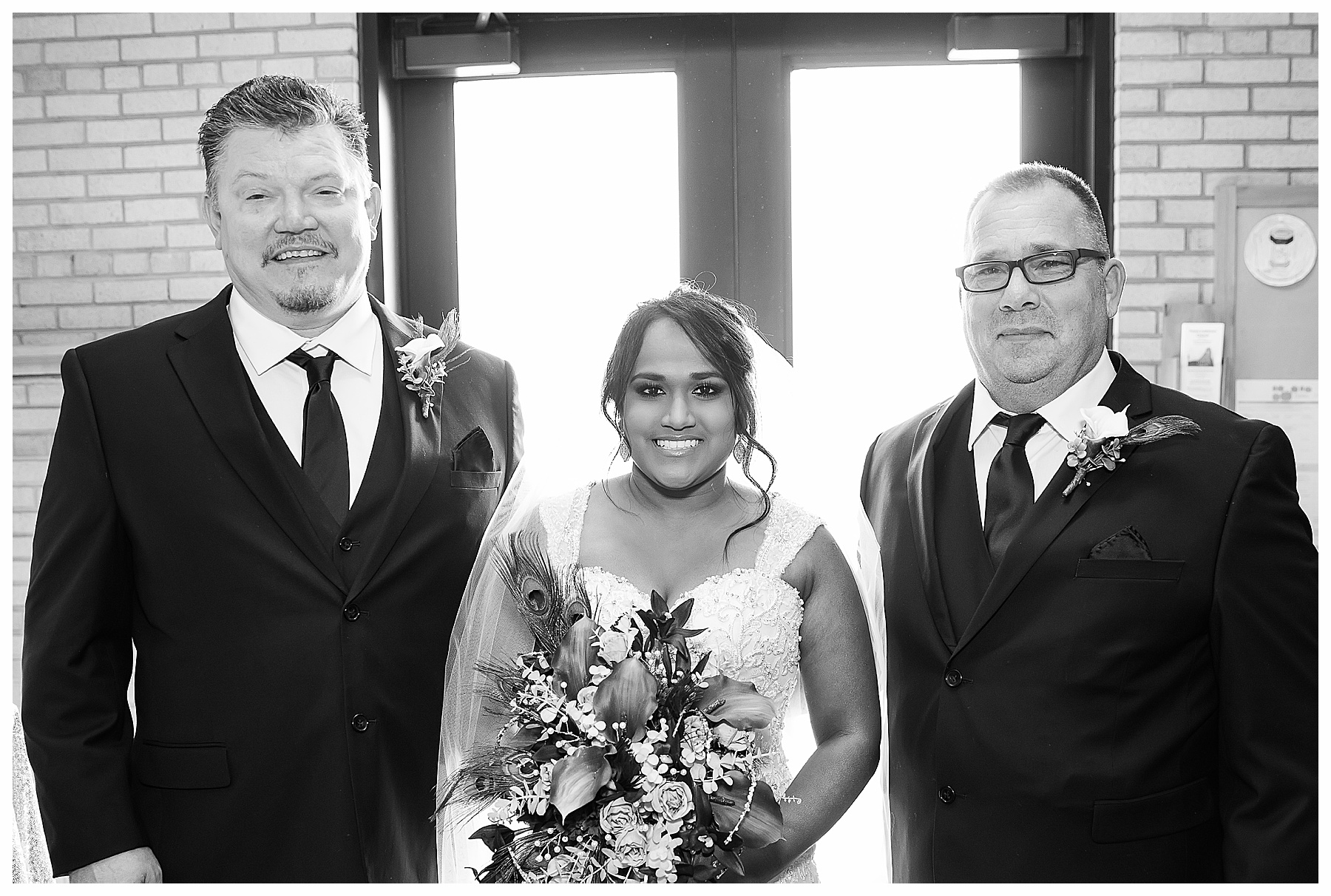 Black and white of bride with her father and step father