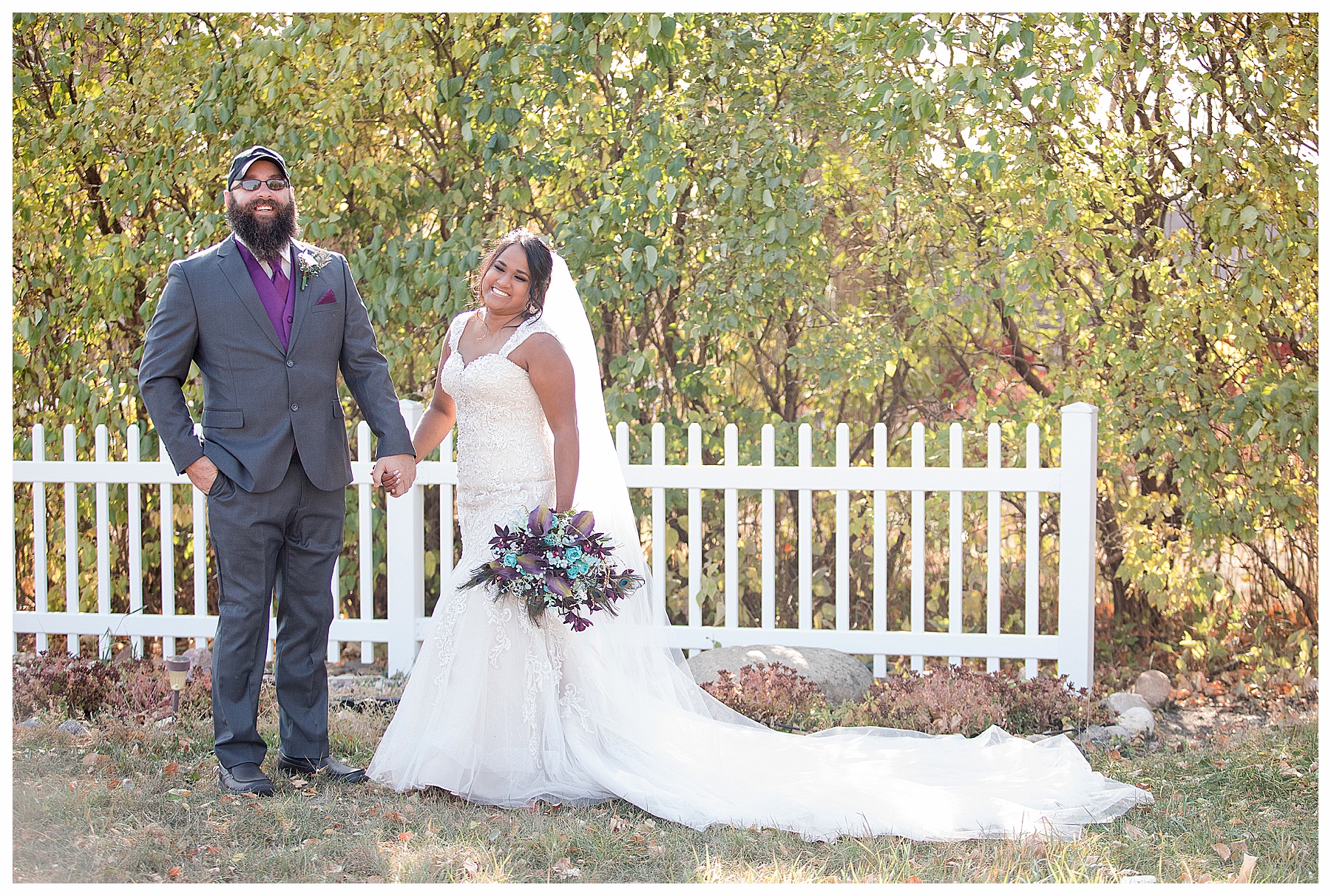 Bride and Groom laugh in front of white picket fence