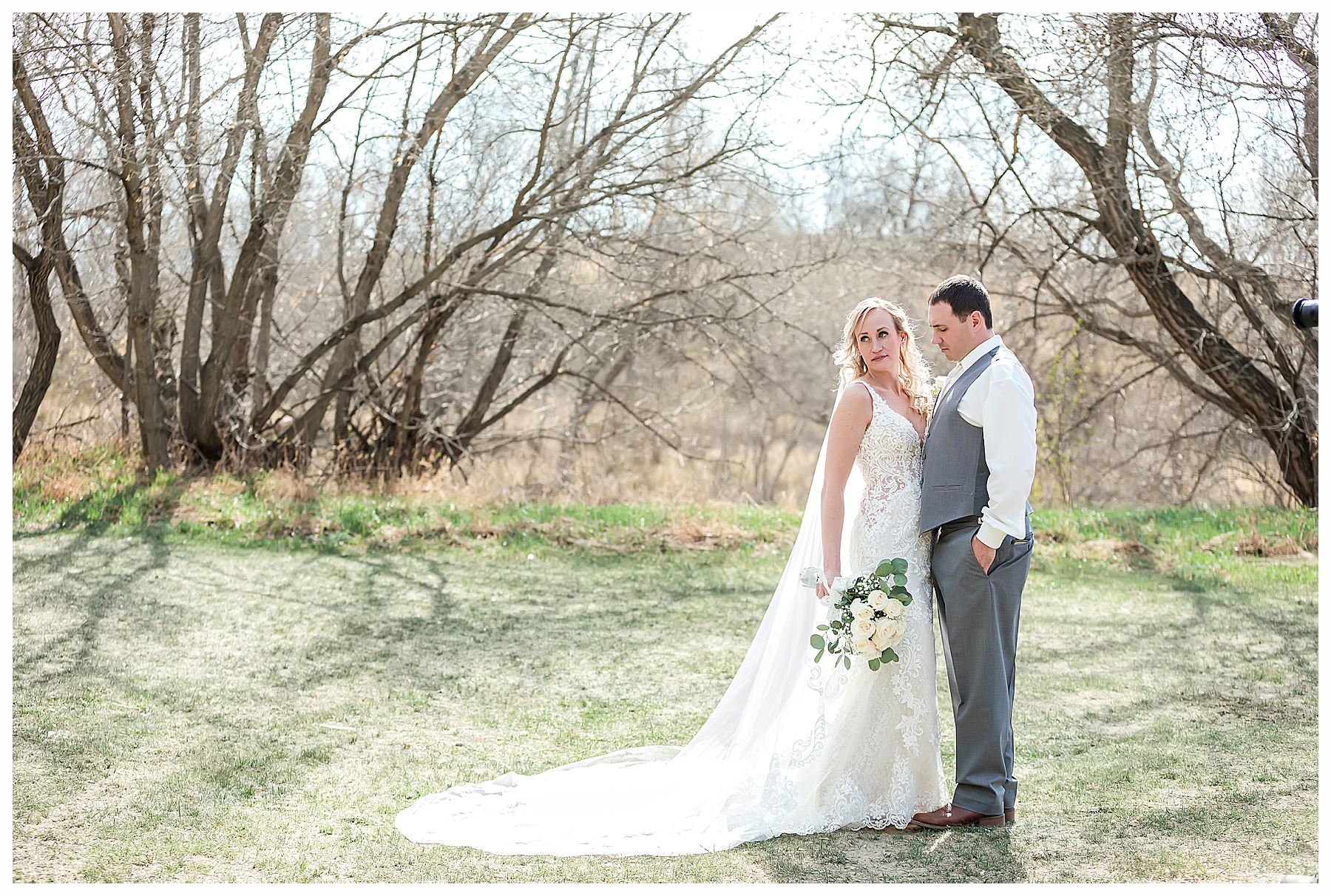 bride in cathedral veil and ivory rose bouquet with groom in grey tux