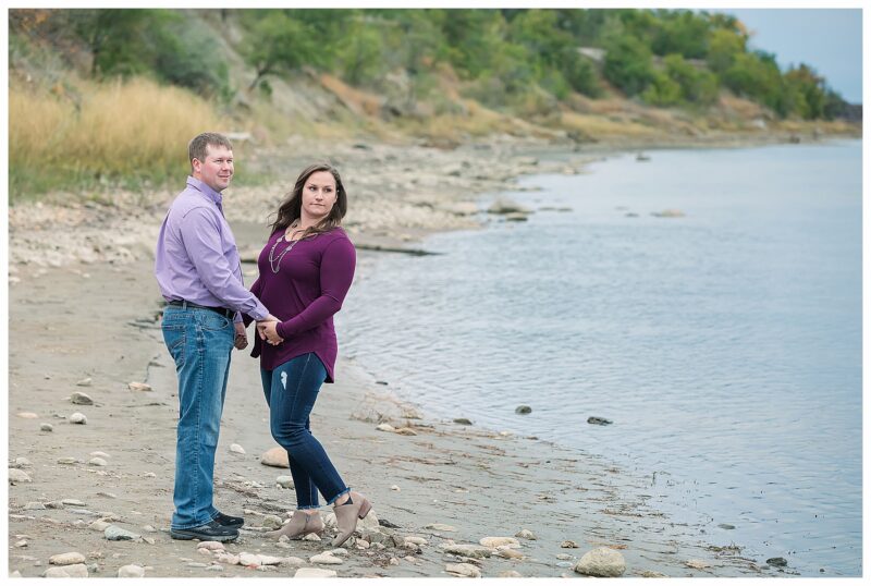 Couple pose by the Missouri River for engagement pictures