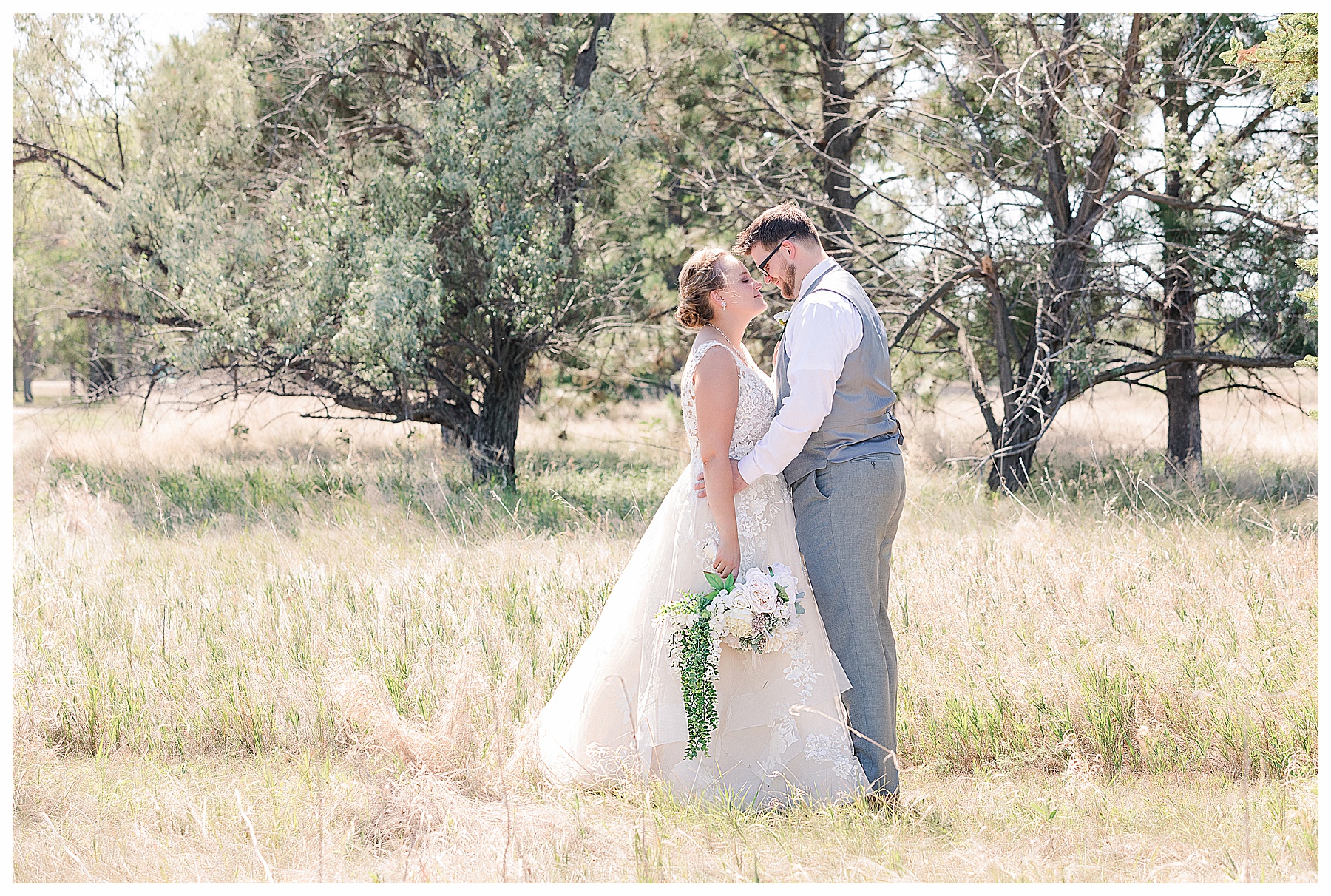 Bride and groom in tall grass by the lake