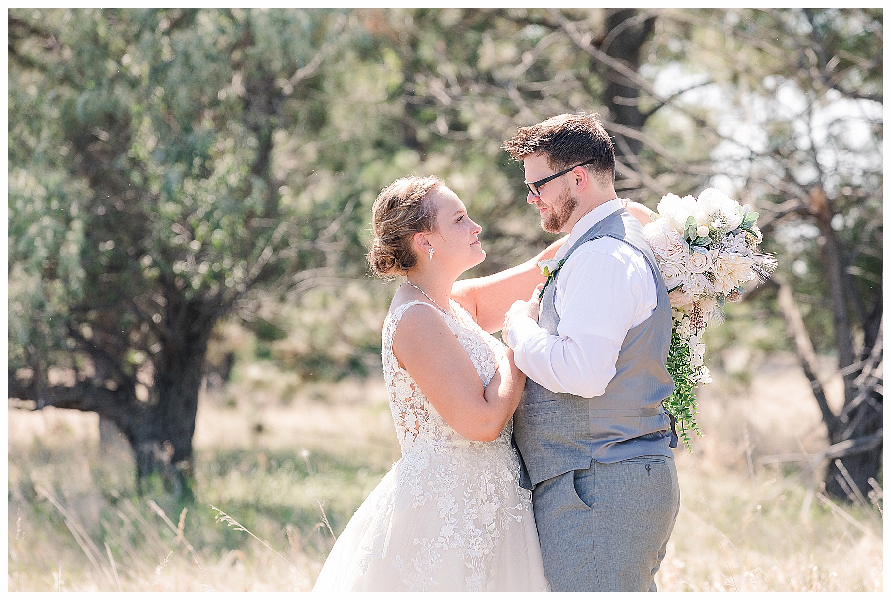 Bride and groom look at each other with bouquet over grooms shoulder