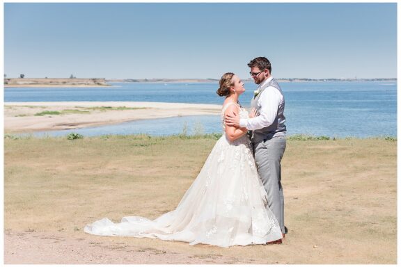 Bride and groom at lake on sunny day