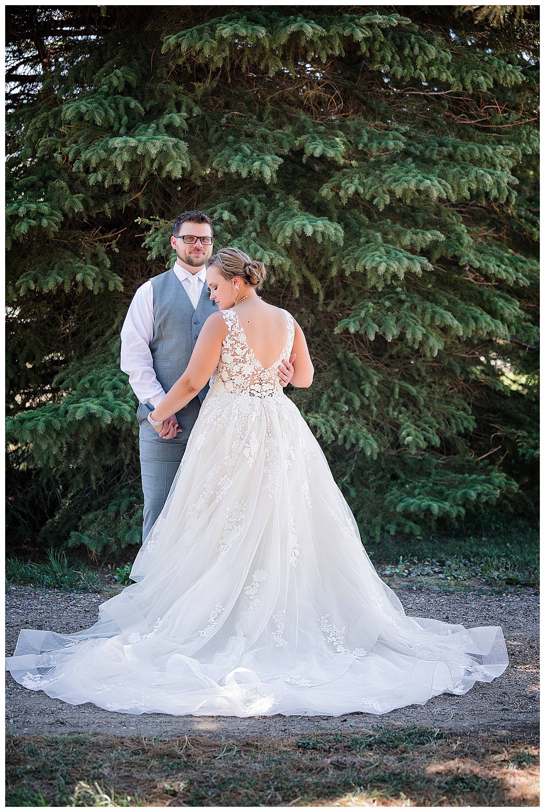 Photo of back of bride's gown and front of groom holding her hand